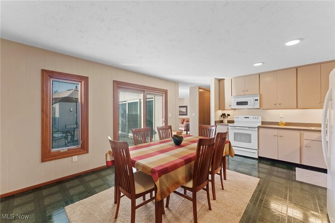 Dining area featuring a textured ceiling, dark flooring, and recessed lighting
