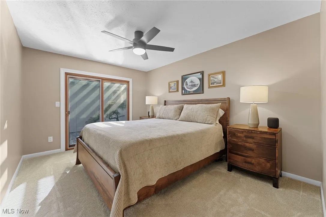 Bedroom featuring light colored carpet, access to exterior, ceiling fan, and a textured ceiling