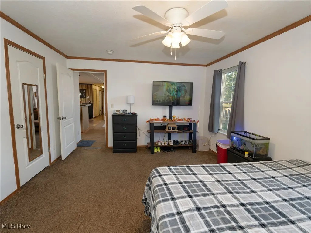 Bedroom with crown molding, dark carpet, and ceiling fan