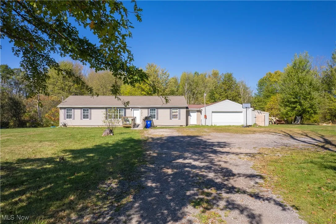 Single story home featuring a front lawn, a garage, gravel driveway, and a lean to shed
