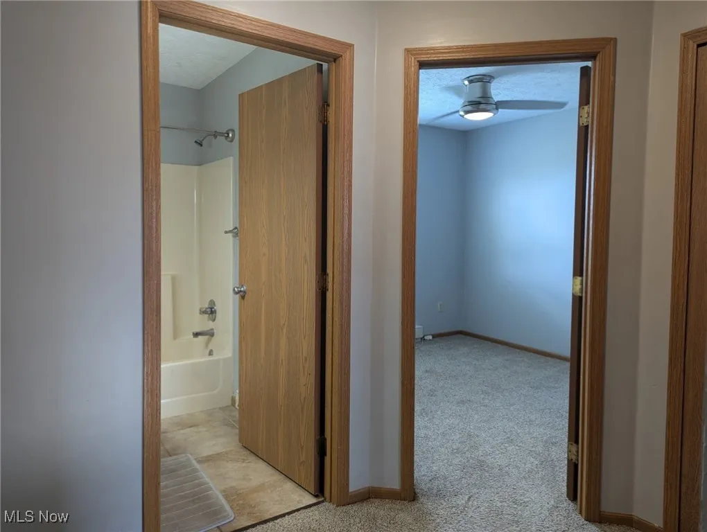 Hall featuring light carpet and a textured ceiling