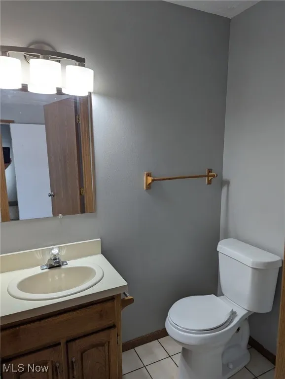 Half bathroom with light tile patterned floors and vanity