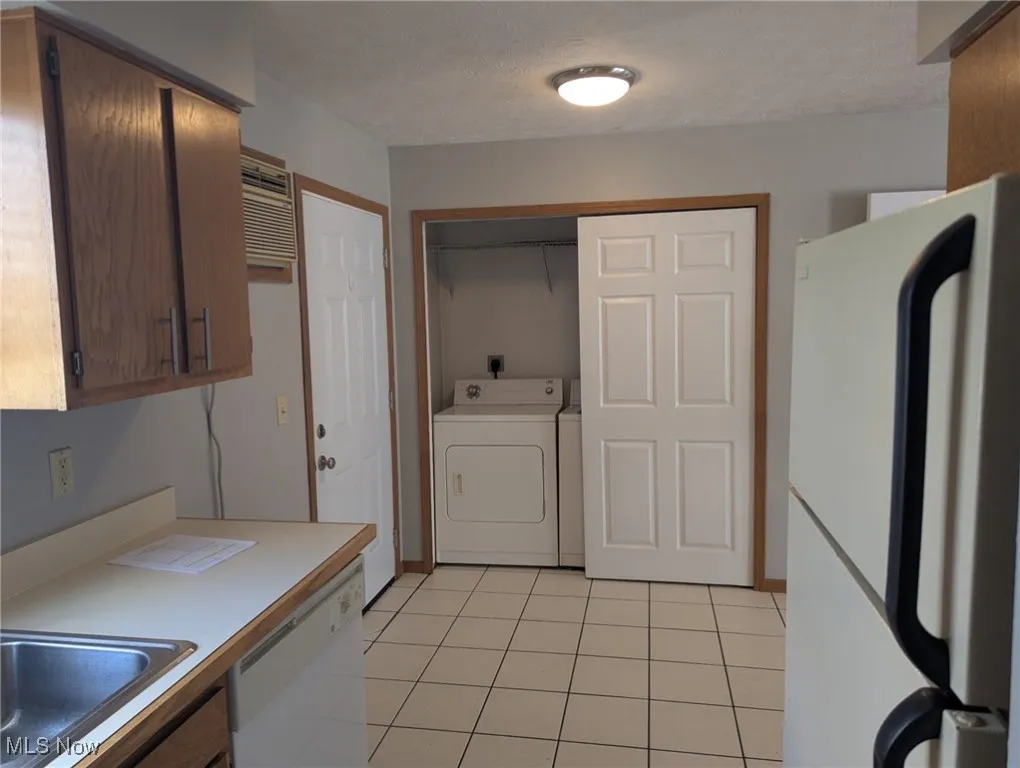 Laundry area with a textured ceiling, light tile patterned floors, and hookup for an electric dryer