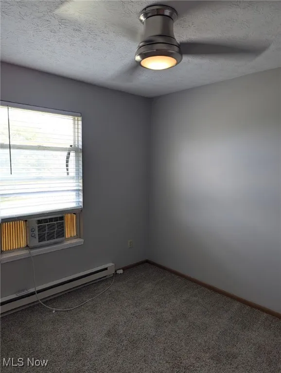 Spare room with a baseboard radiator, a textured ceiling, carpet, and cooling unit