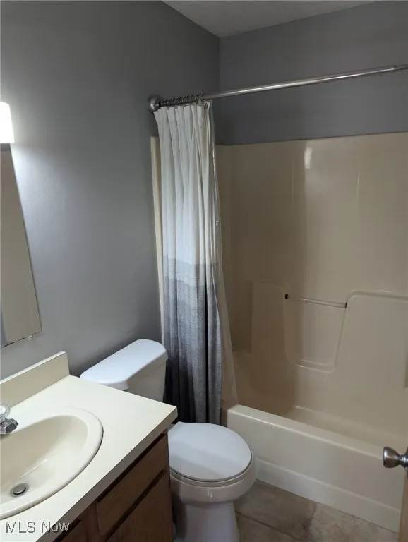 Bathroom featuring shower / bathtub combination with curtain, vanity, and light tile patterned floors