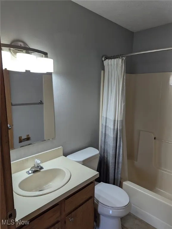 Bathroom featuring shower / bath combo with shower curtain, vanity, and a textured ceiling