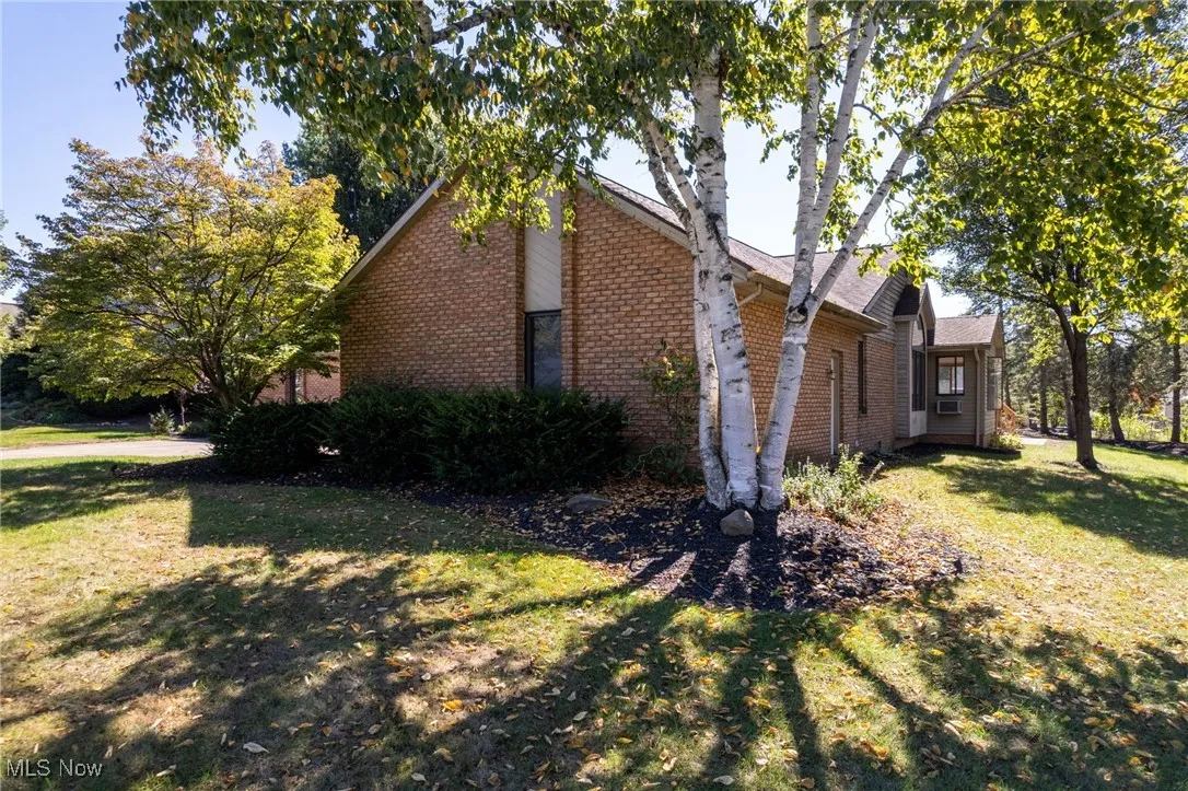 View of property exterior with a yard and brick siding