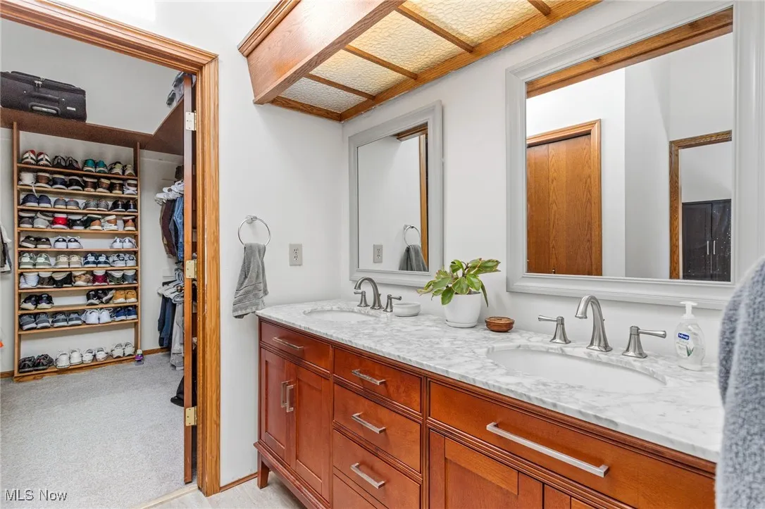 Full bathroom featuring double vanity and a spacious closet