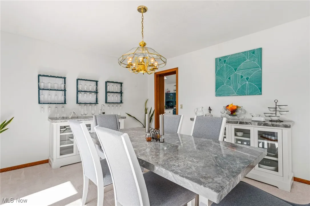 Dining space featuring light carpet and a chandelier