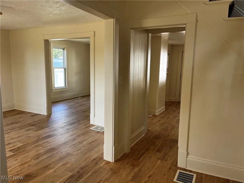 Corridor featuring a textured ceiling and wood finished floors
