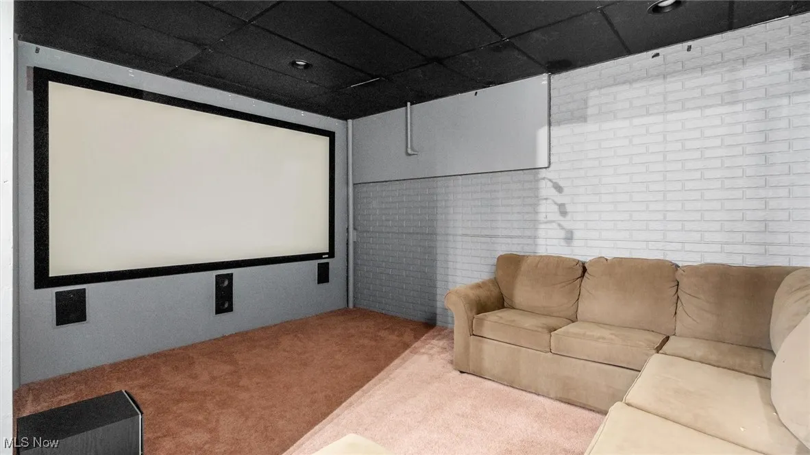 Cinema room with carpet flooring and brick wall