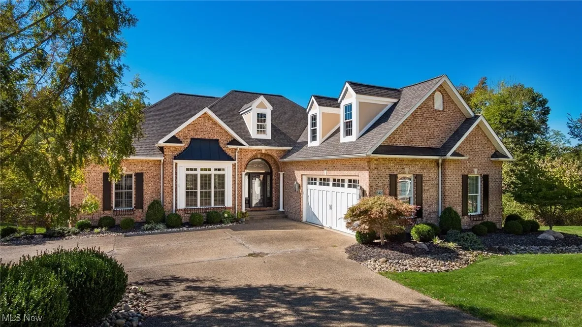 View of front of home featuring concrete driveway, brick siding, a front lawn, and a shingled roof