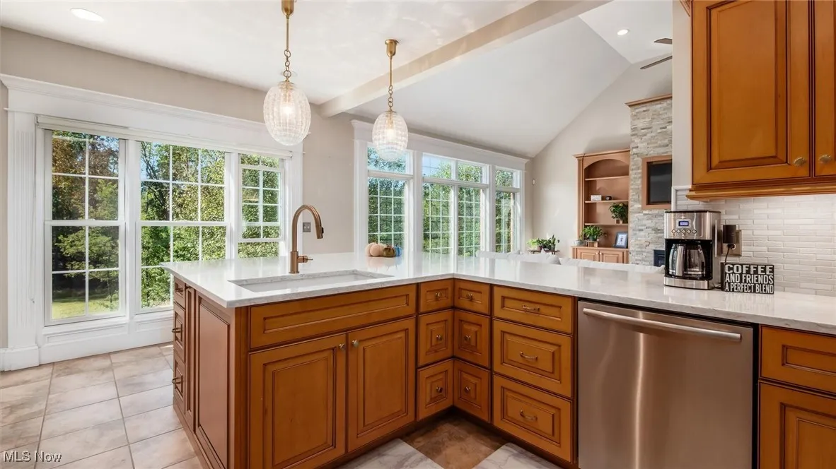 Kitchen featuring brown cabinets, dishwasher, light stone countertops, tasteful backsplash, and recessed lighting
