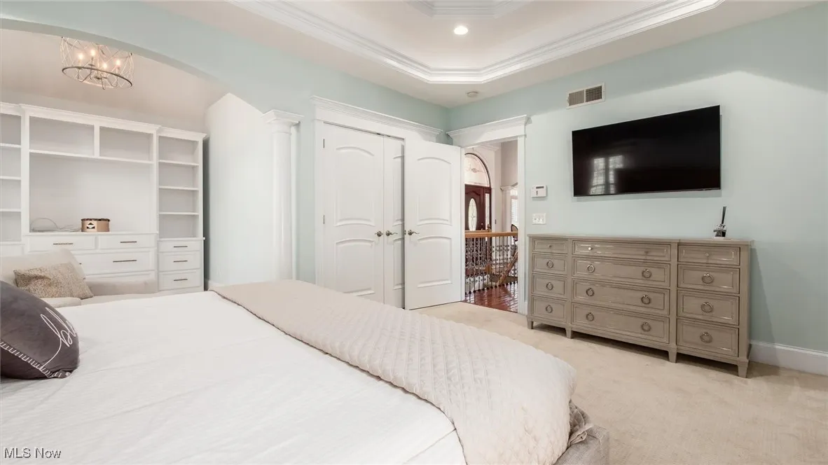 Bedroom featuring light colored carpet, arched walkways, crown molding, a tray ceiling, and recessed lighting