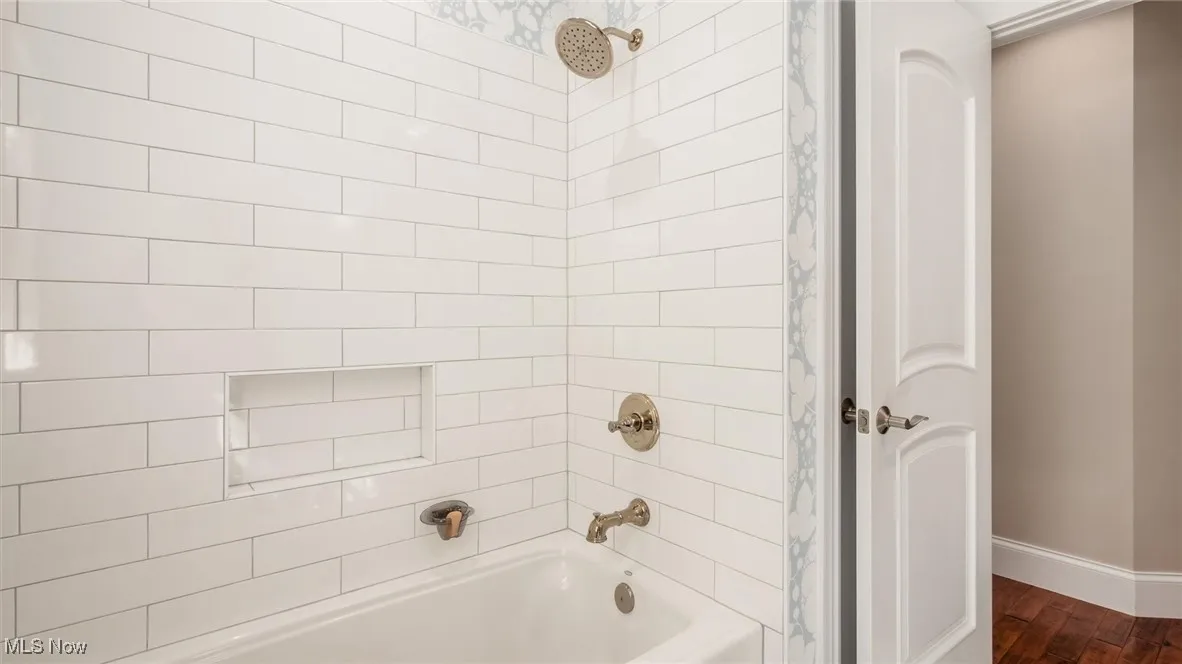 Bathroom with tub / shower combination and dark wood finished floors