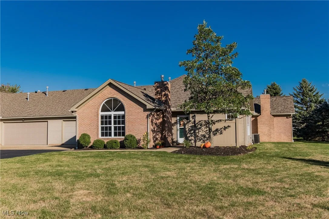 Single story home featuring brick siding, a front yard, an attached garage, and roof with shingles