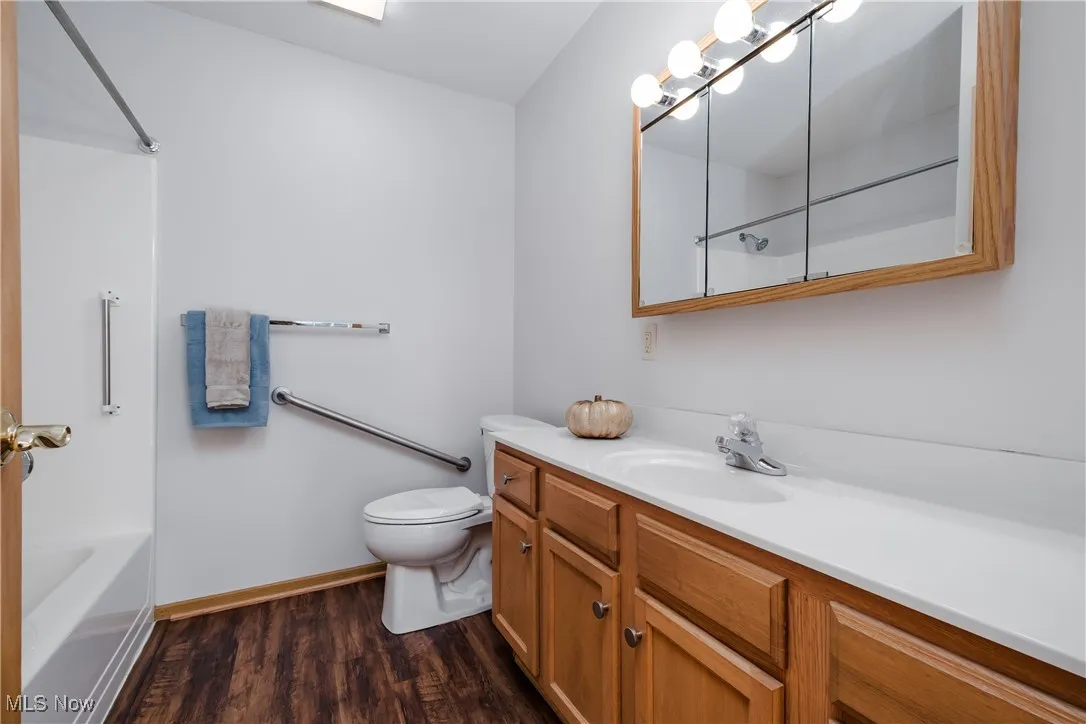 Master bathroom featuring dark wood-style flooring, vanity, and shower / bath combination
