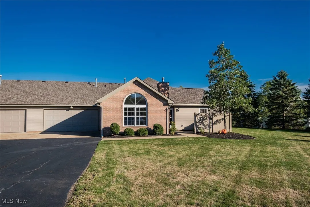 Single story home with driveway, an attached garage, a front lawn, and a shingled roof