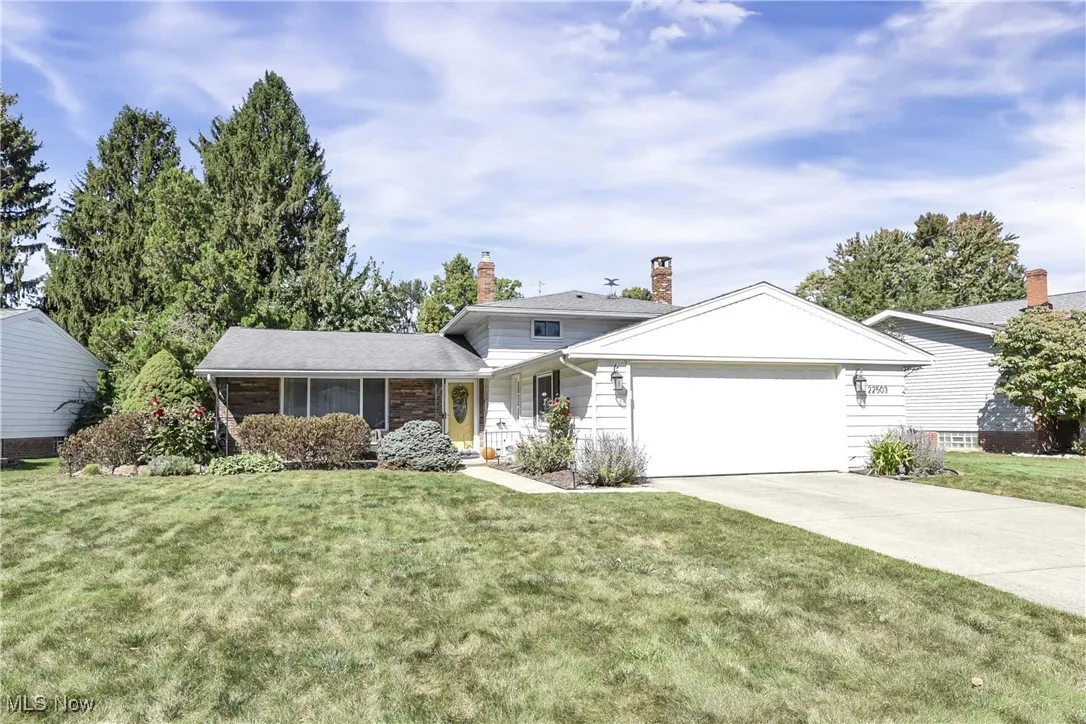 View of front of property featuring a chimney, a front yard, concrete driveway, and a garage
