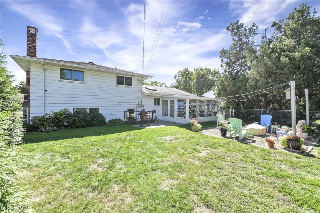 Back of property with a patio, a chimney, a lawn, and a sunroom