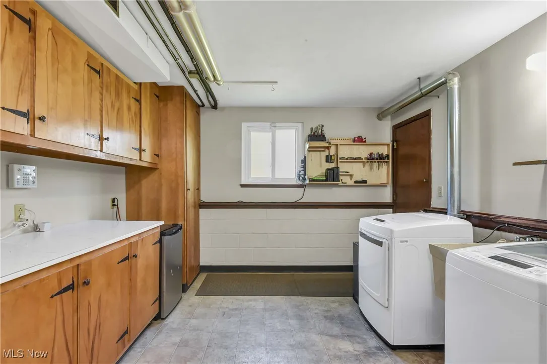 Washroom featuring wainscoting, independent washer and dryer, light flooring, and cabinet space