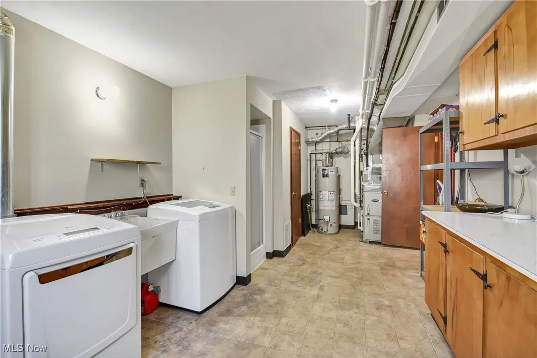 Laundry room with gas water heater, separate washer and dryer, and cabinet space