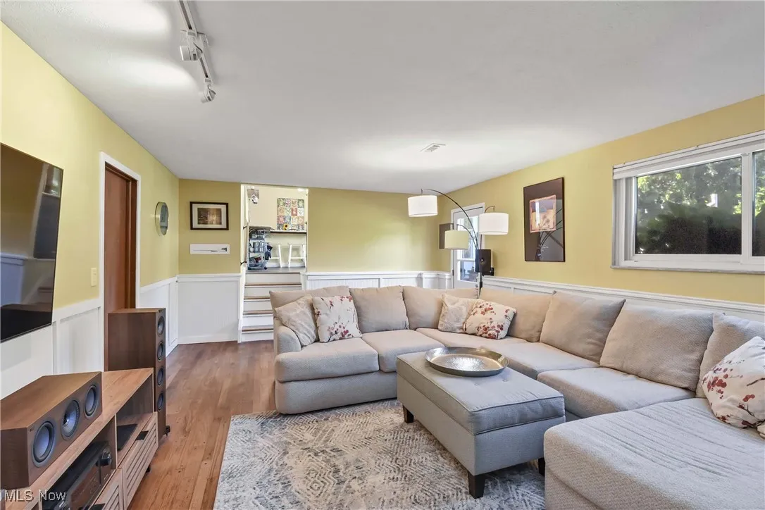 Living area featuring wood finished floors, track lighting, and wainscoting