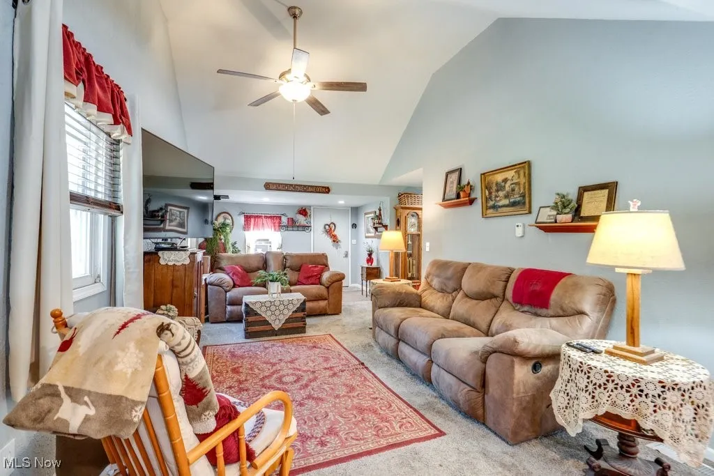 Living room with high vaulted ceiling, carpet, and a ceiling fan