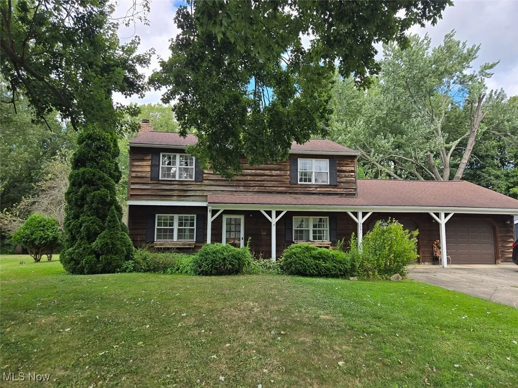 View of front facade with a front lawn, a garage, and driveway