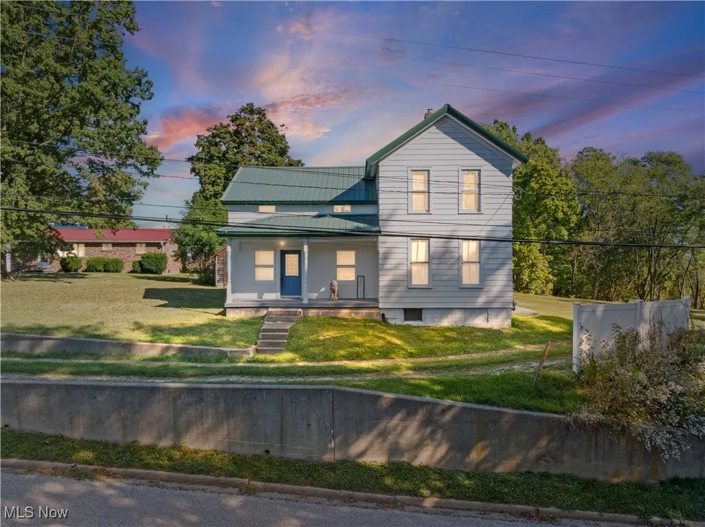 View of front of property with a porch, a front lawn, a  metal roof