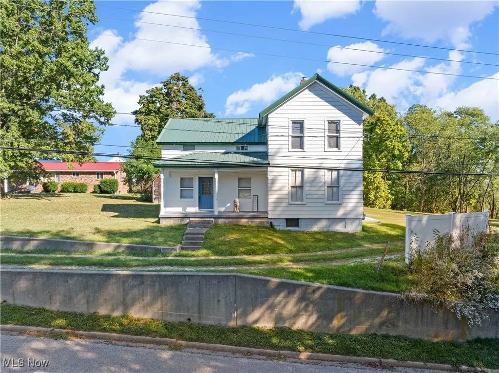 View of front of home featuring covered porch, a front yard, a metal roof, and a standing seam roof