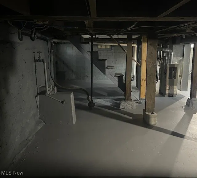 Unfinished below grade area with stairs and heating unit