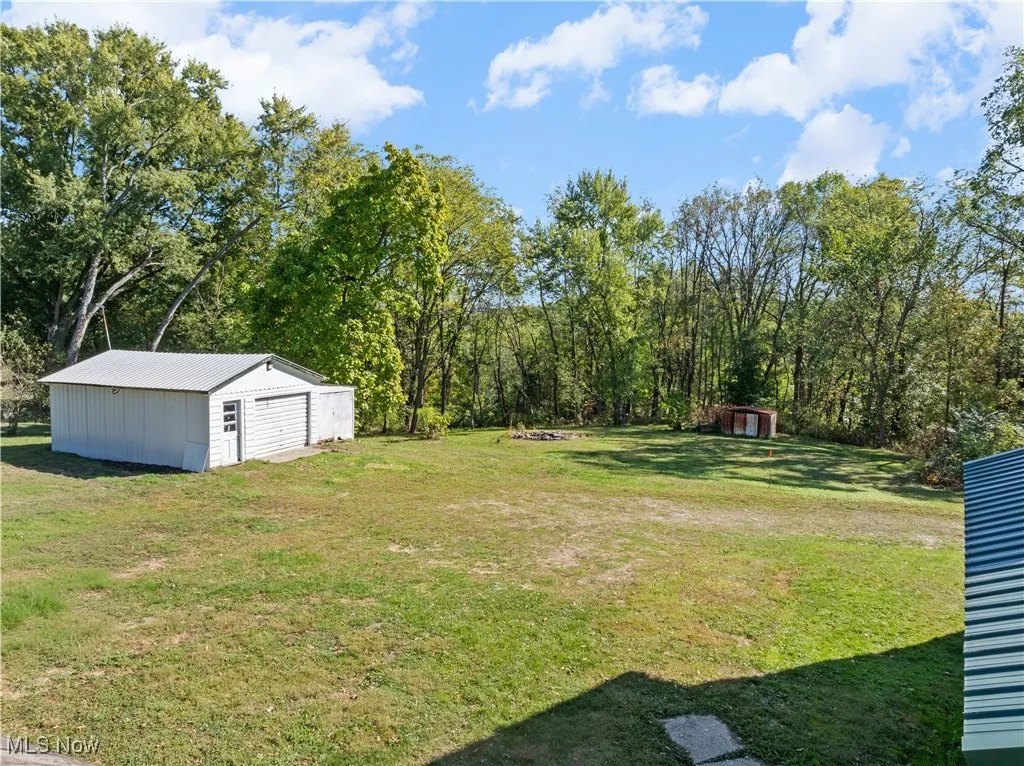 View of green lawn with an outdoor structure and a garage