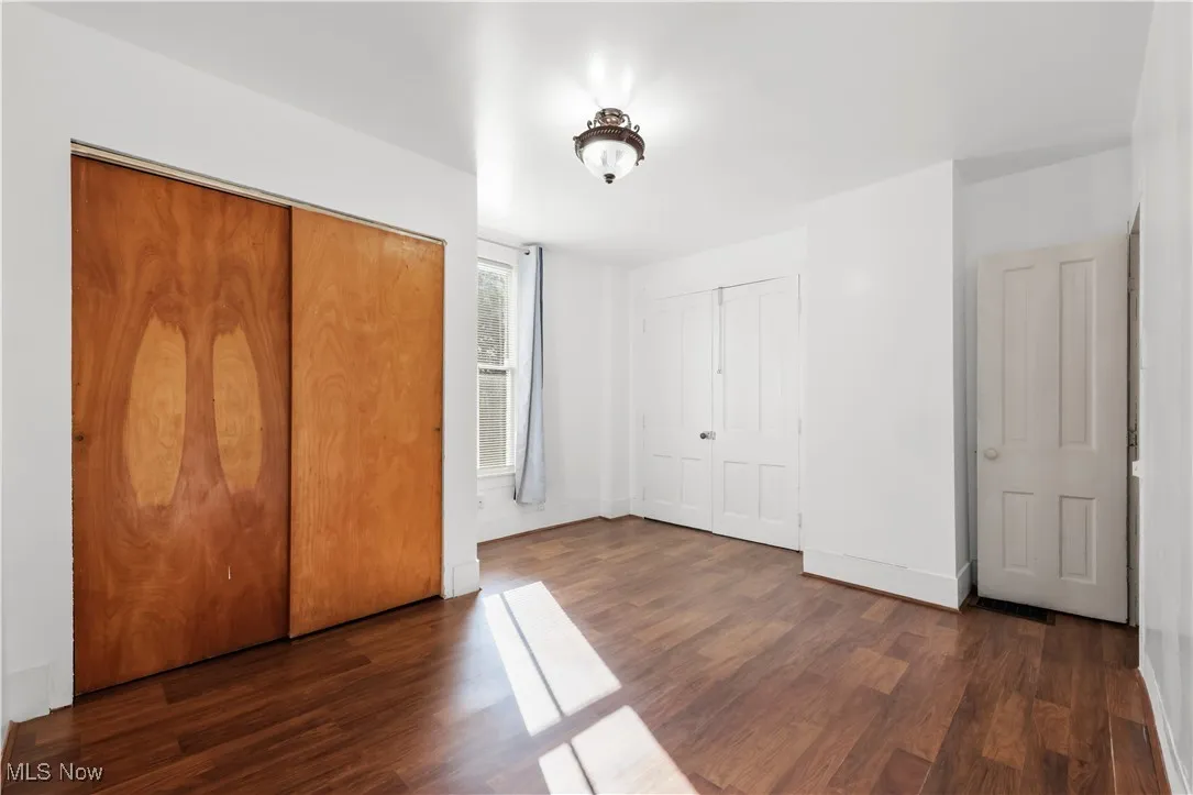 Unfurnished bedroom with two closets and dark wood-style floors