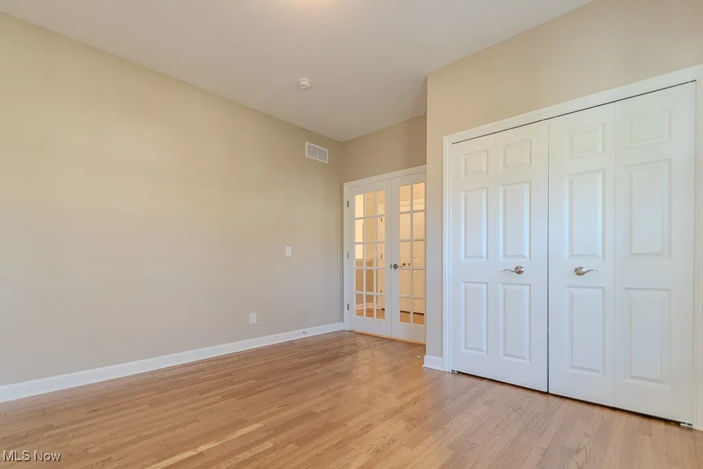 Unfurnished bedroom featuring french doors, light wood-style floors, and a closet