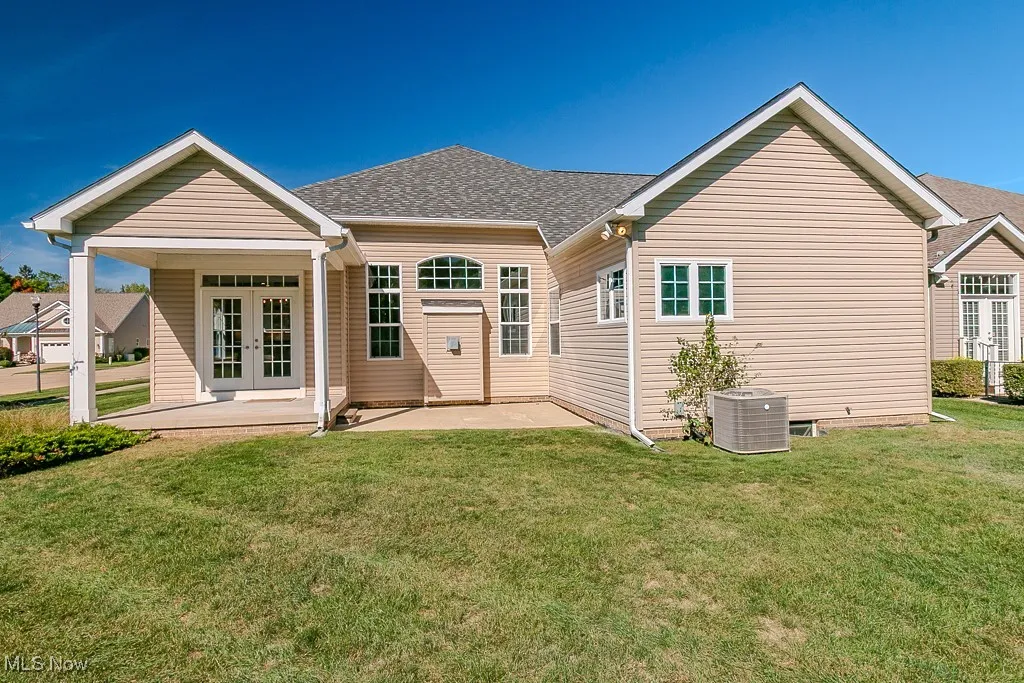 Back of property featuring french doors, a patio, a yard, and roof with shingles