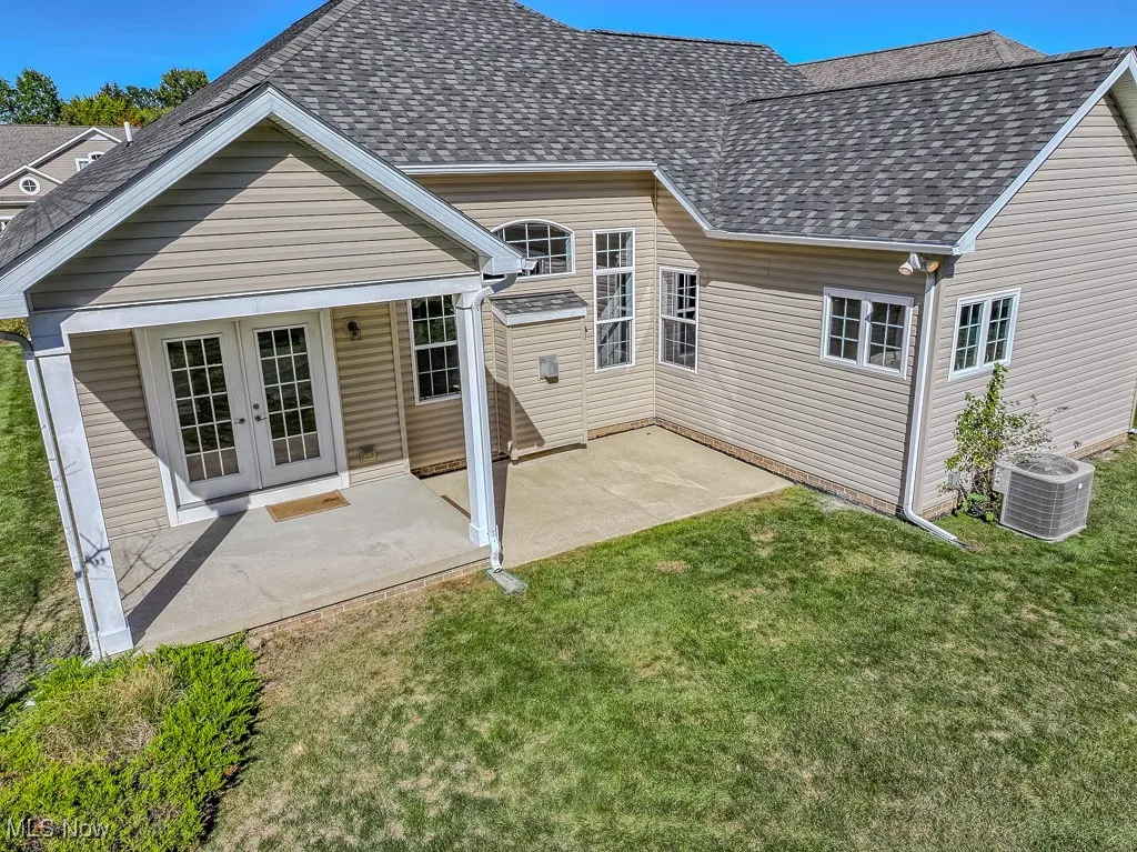 Back of house featuring a patio area, roof with shingles, a lawn, and french doors