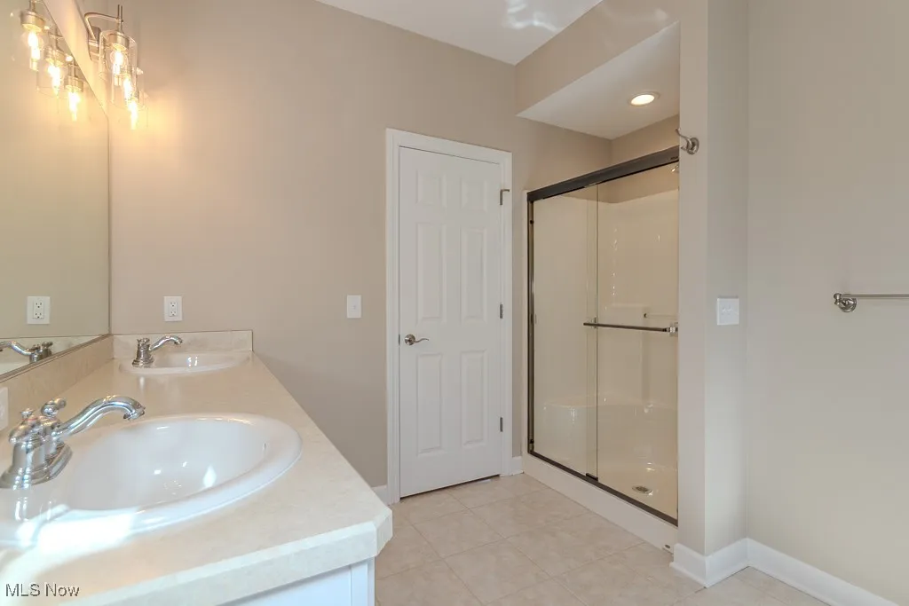 Bathroom featuring a stall shower, double vanity, and light tile patterned floors