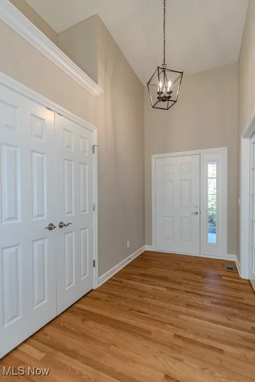 Foyer featuring a chandelier, light wood finished floors, and a towering ceiling