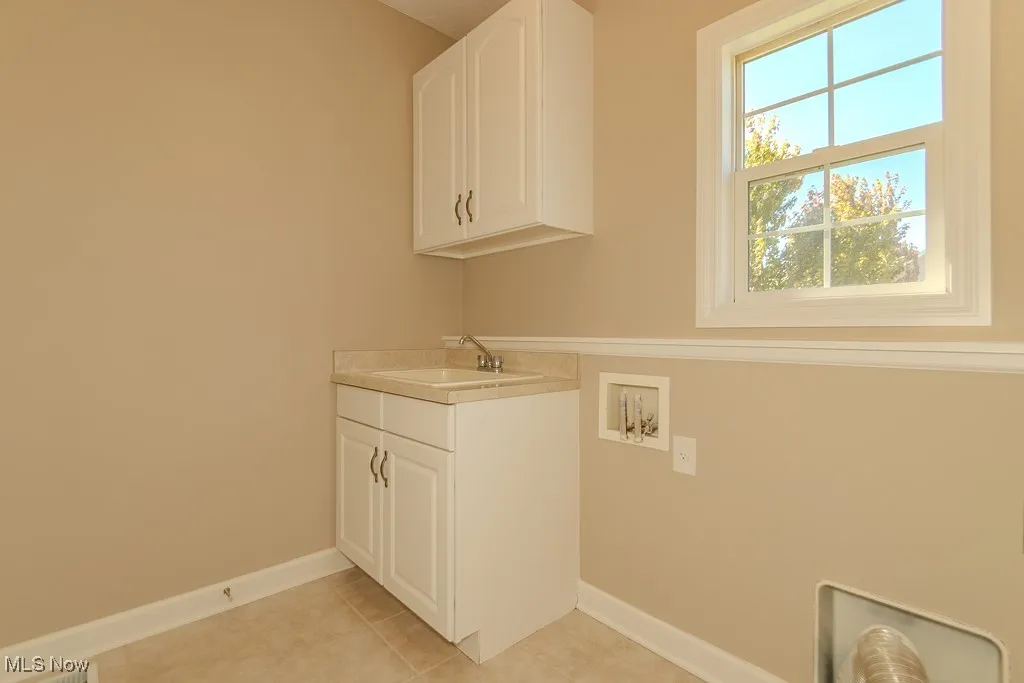 Laundry area featuring cabinet space, hookup for a washing machine, and light tile patterned flooring