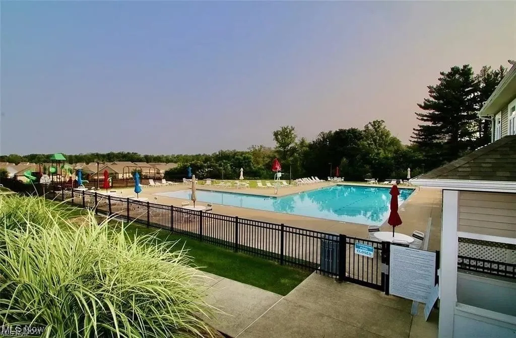 Community pool with a patio area and view of scattered trees