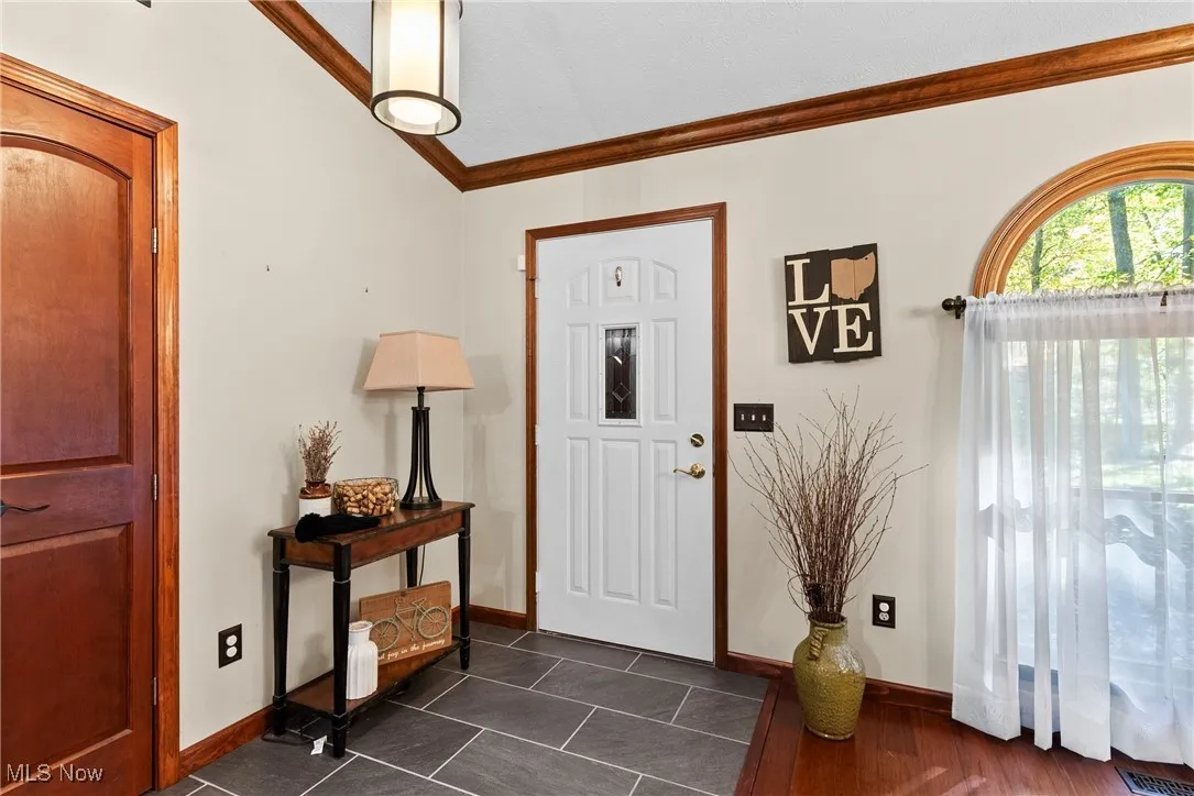 Entrance foyer featuring ornamental molding and dark tile patterned flooring