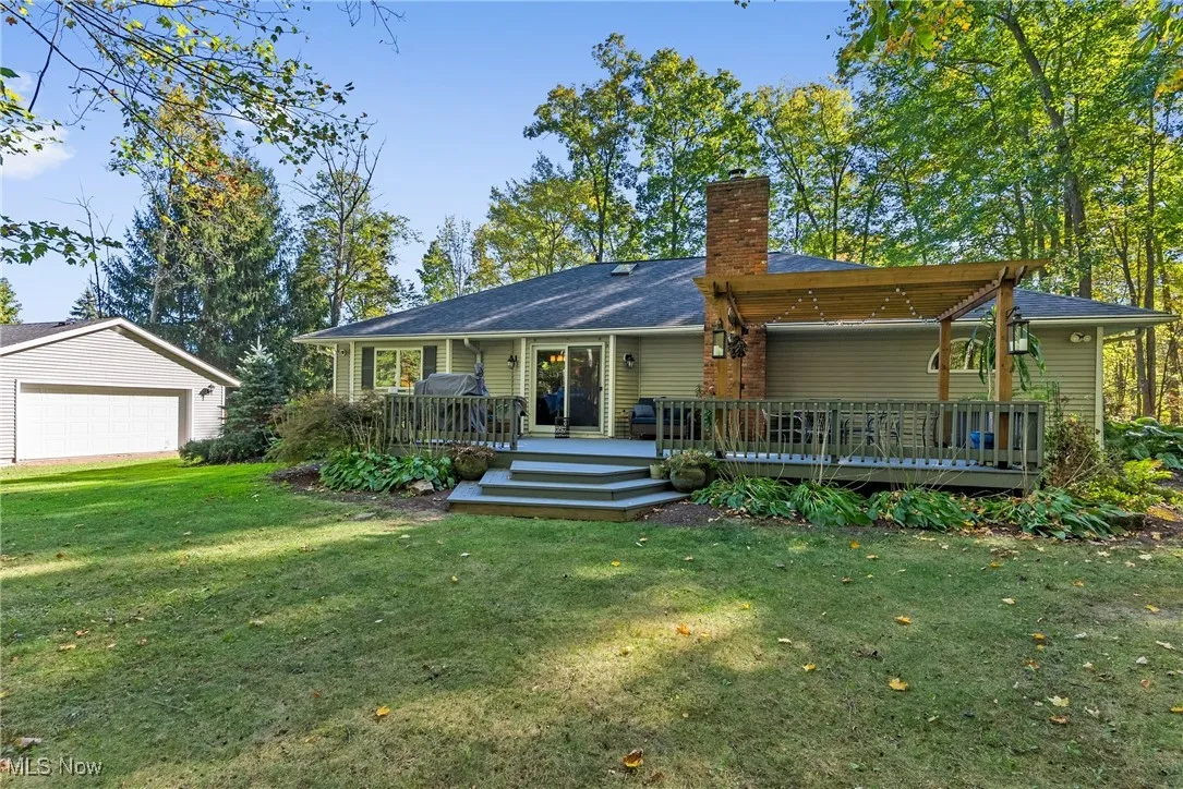 Rear view of house with a yard, a chimney, a deck, and a garage