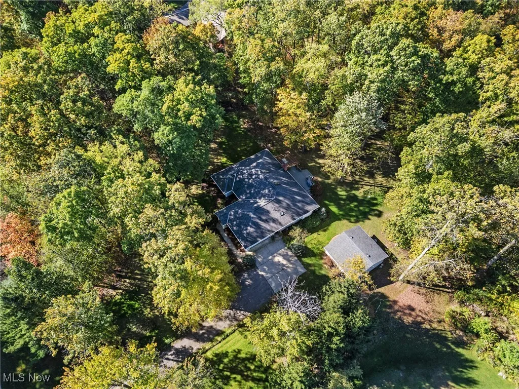 Aerial view of property and surrounding area with a heavily wooded area