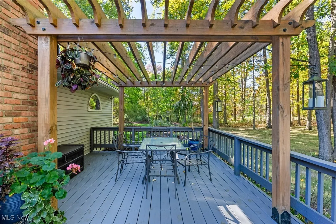 Wooden deck featuring outdoor dining space and view of wooded area