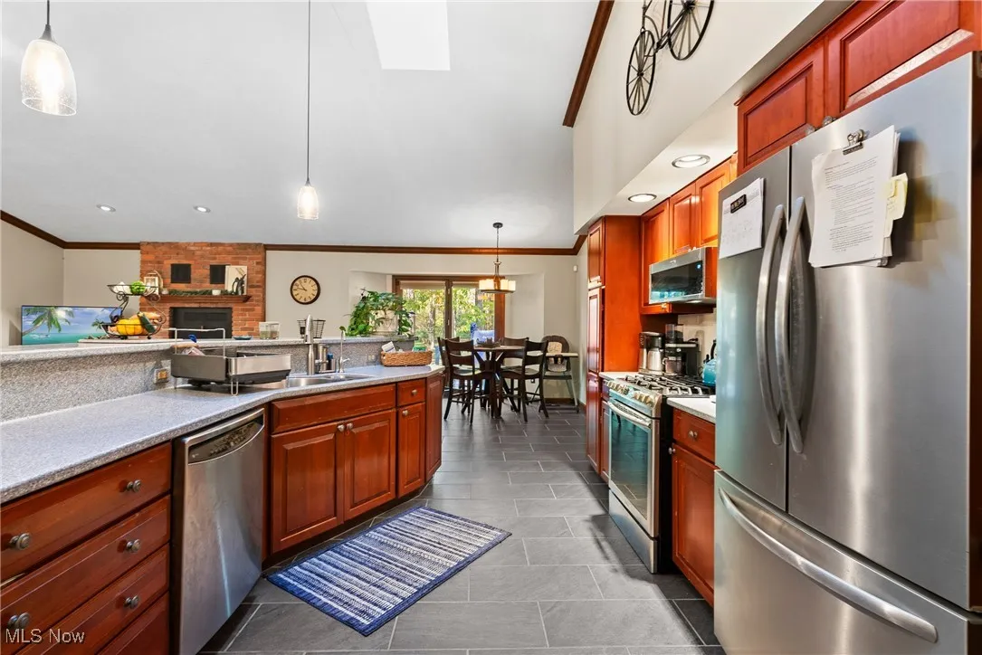 Kitchen featuring decorative light fixtures, stainless steel appliances, recessed lighting, crown molding, and light stone counters
