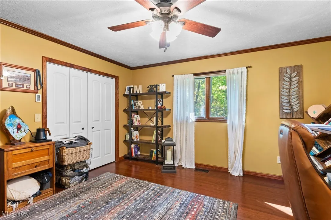 Home office with crown molding, dark wood-style floors, and a ceiling fan