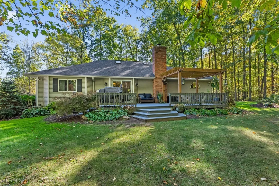 Back of house featuring a yard, a wooden deck, and a chimney