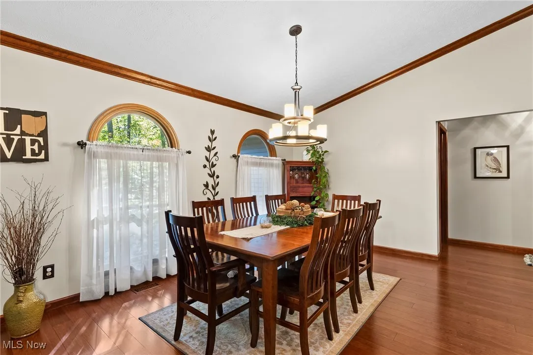 Dining room featuring crown molding, wood finished floors, and a chandelier