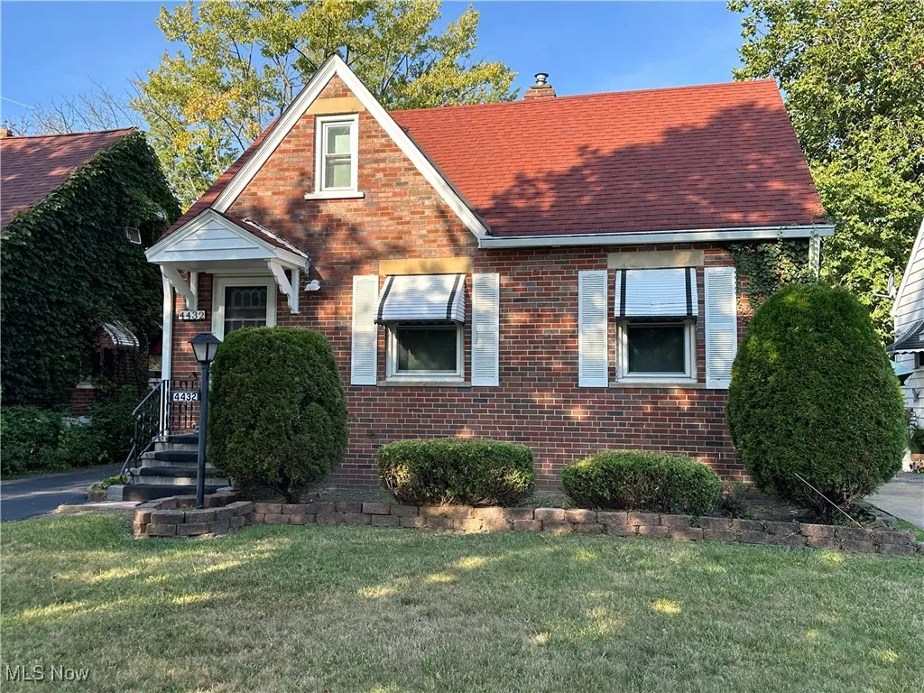 View of front of property with a front lawn, brick siding, a chimney, and a shingled roof